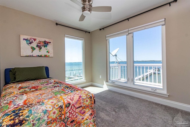 carpeted bedroom featuring a water view and ceiling fan