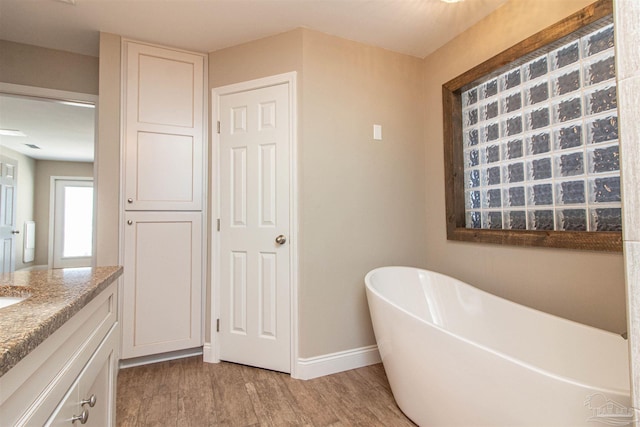 bathroom featuring vanity, hardwood / wood-style floors, and a bath