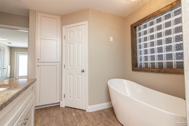 full bathroom featuring baseboards, a soaking tub, vanity, and wood finished floors