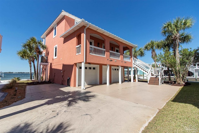 view of front of home featuring stucco siding, driveway, stairs, and a garage