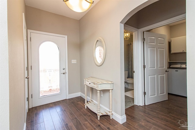 entrance foyer featuring arched walkways, baseboards, and dark wood-style floors