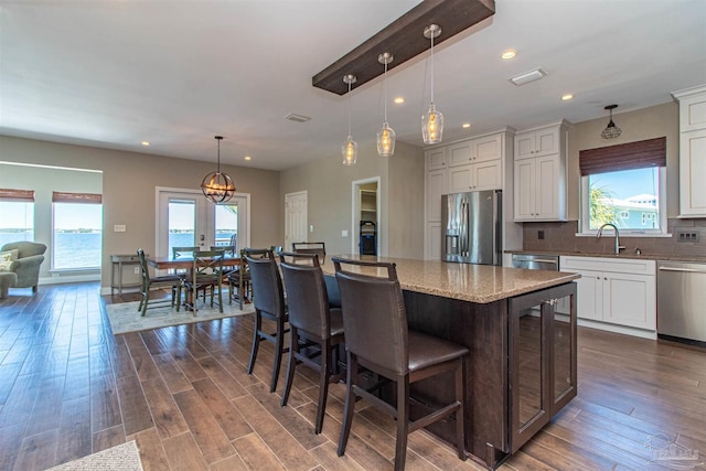 kitchen with appliances with stainless steel finishes, wood-type flooring, decorative backsplash, and plenty of natural light