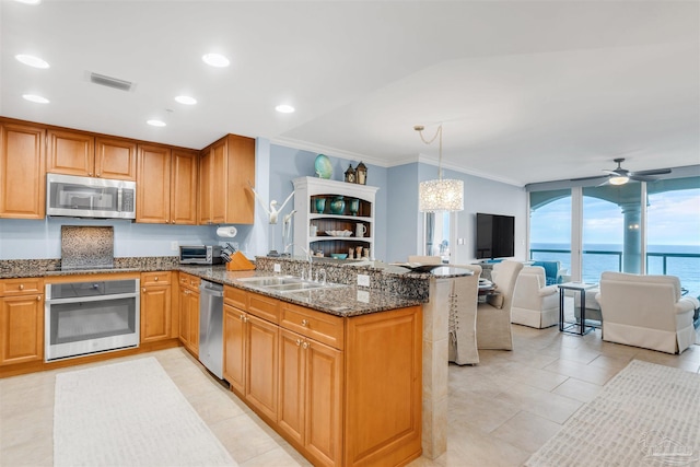 kitchen with sink, hanging light fixtures, dark stone countertops, appliances with stainless steel finishes, and kitchen peninsula