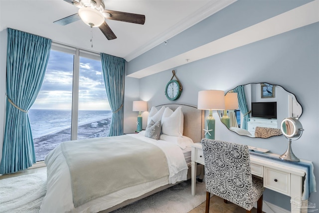 bedroom featuring a water view, built in desk, ornamental molding, expansive windows, and ceiling fan