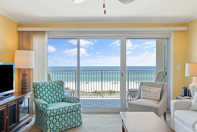 living room featuring a water view, a healthy amount of sunlight, and a view of the beach