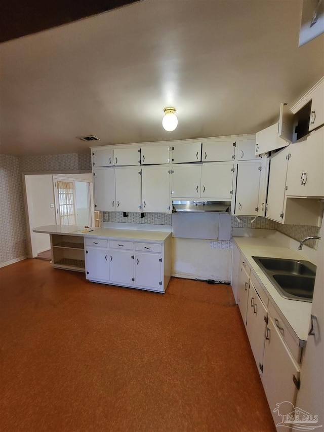 kitchen with visible vents, a sink, wallpapered walls, white cabinets, and light countertops