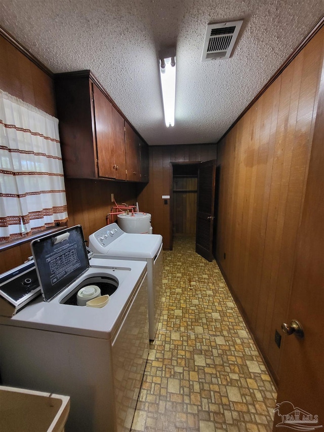 washroom with cabinet space, washing machine and dryer, visible vents, and wood walls