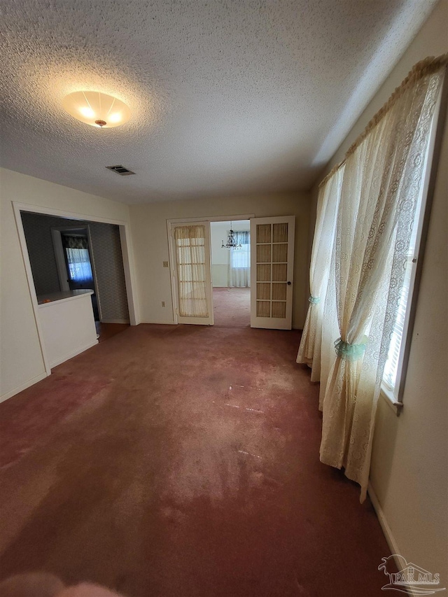 unfurnished room featuring a wealth of natural light, visible vents, and carpet flooring