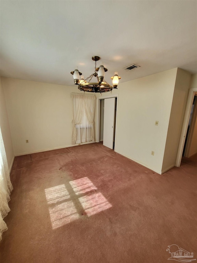 empty room featuring a chandelier, visible vents, light carpet, and baseboards