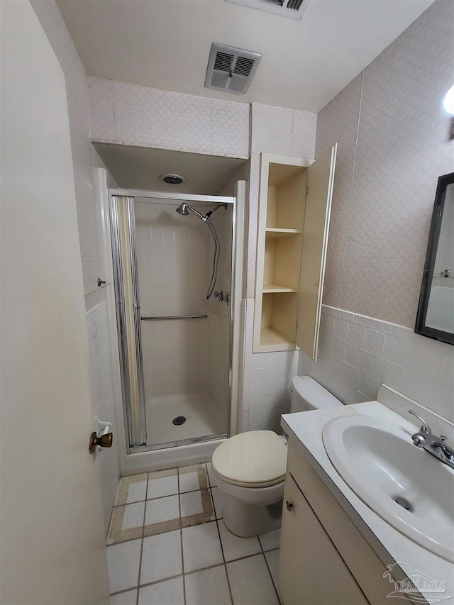 bathroom featuring tile patterned flooring, visible vents, vanity, a stall shower, and tile walls