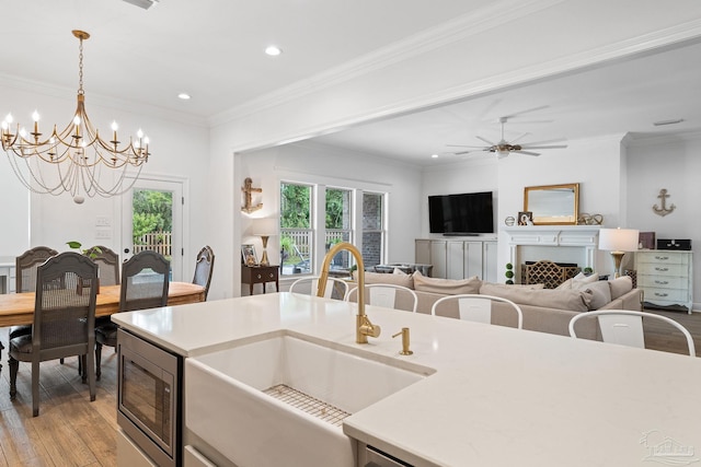 kitchen with sink, crown molding, ceiling fan with notable chandelier, and light hardwood / wood-style floors