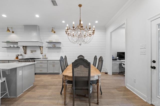 dining room with light hardwood / wood-style flooring, a chandelier, and crown molding