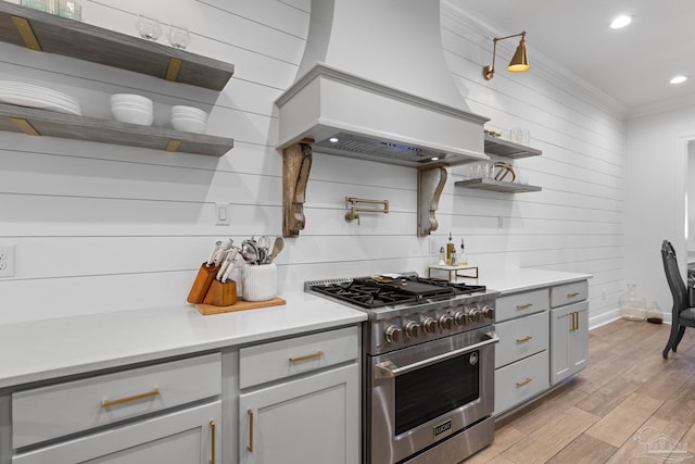 kitchen with premium range hood, light wood-type flooring, gray cabinetry, stainless steel range, and crown molding