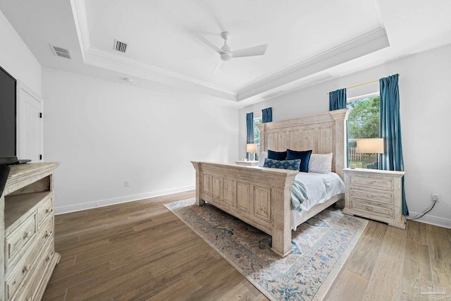 bedroom featuring ceiling fan, a raised ceiling, ornamental molding, and dark hardwood / wood-style floors