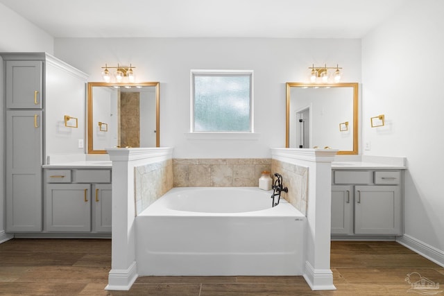 bathroom featuring vanity, hardwood / wood-style floors, and a bath