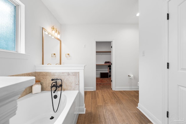 bathroom featuring toilet, hardwood / wood-style flooring, and a washtub