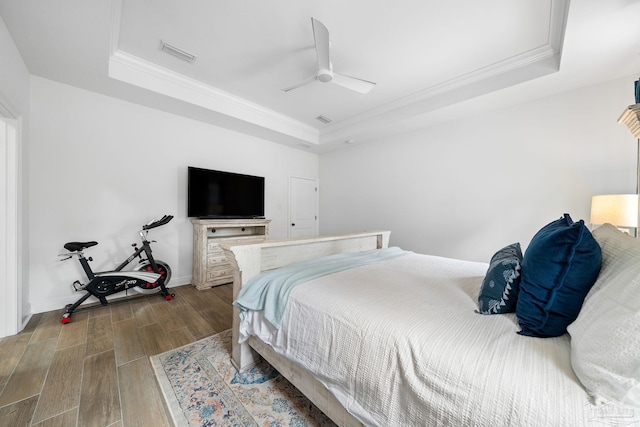 bedroom with ceiling fan, a raised ceiling, and hardwood / wood-style floors