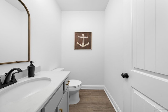 bathroom with toilet, hardwood / wood-style flooring, and vanity