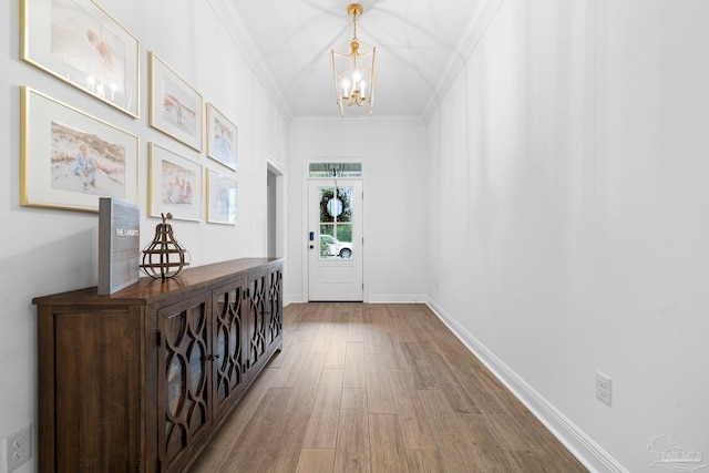 doorway to outside with a notable chandelier, ornamental molding, and hardwood / wood-style flooring