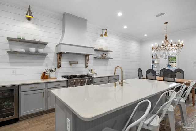 kitchen featuring high end stove, hardwood / wood-style flooring, a breakfast bar area, wine cooler, and custom exhaust hood