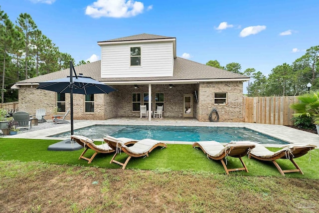 rear view of property with a patio, a fenced in pool, and a yard