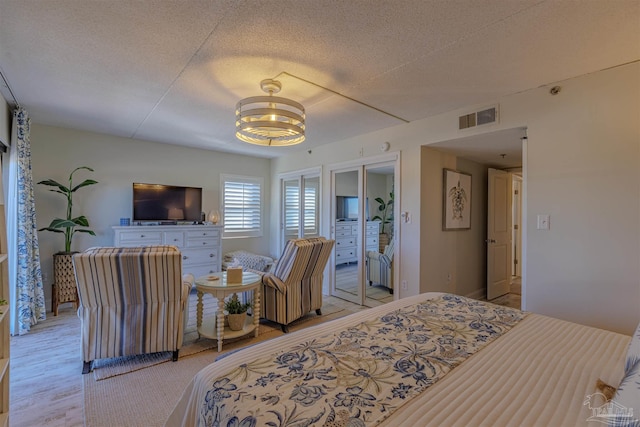 bedroom with an inviting chandelier, multiple closets, visible vents, and a textured ceiling