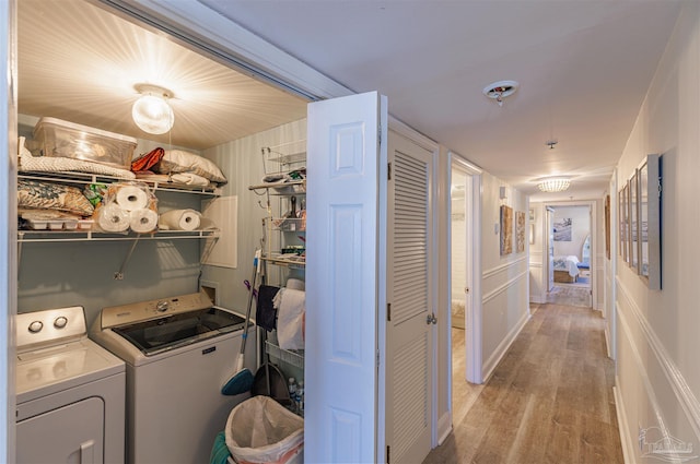 clothes washing area with laundry area, washing machine and dryer, and light wood-type flooring