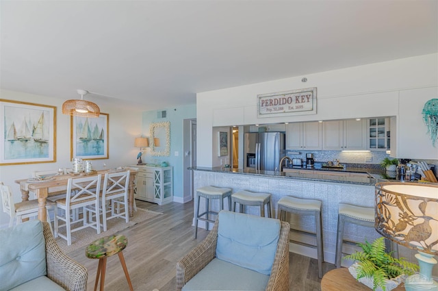 kitchen with decorative backsplash, stainless steel fridge, glass insert cabinets, and wood finished floors