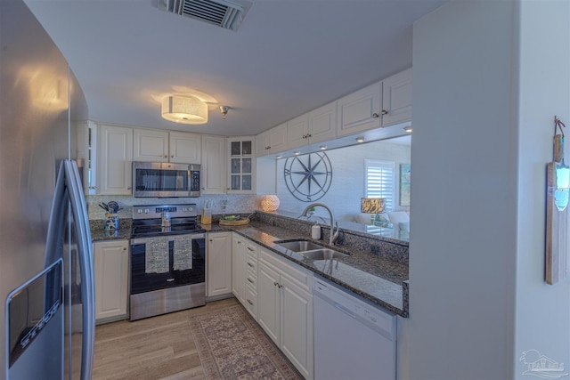 kitchen featuring visible vents, dark stone counters, a sink, stainless steel appliances, and white cabinetry