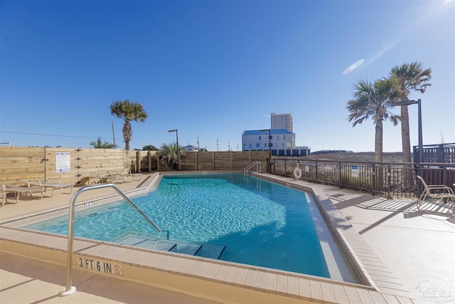 community pool with a patio area and fence