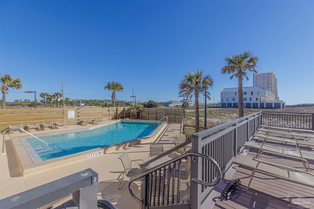 community pool with a patio area and fence