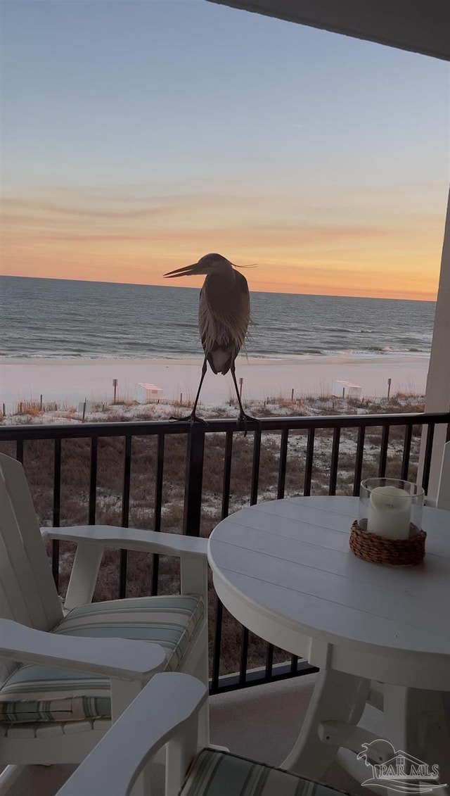 balcony at dusk with a beach view and a water view