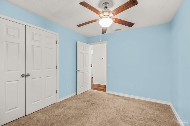 unfurnished bedroom with light colored carpet, ceiling fan, and a closet