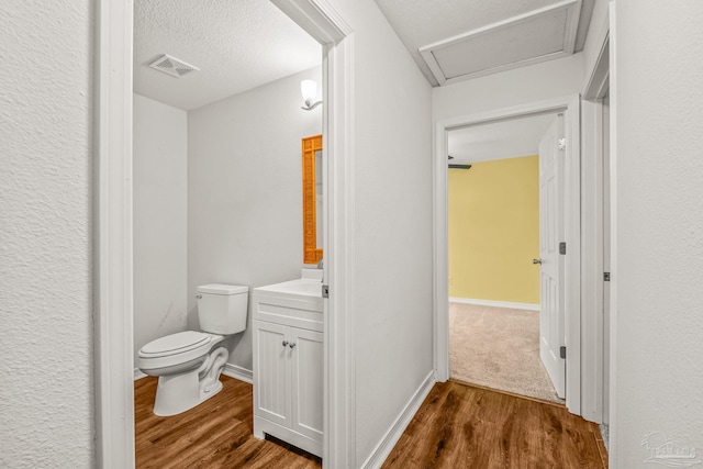 bathroom with hardwood / wood-style floors, vanity, a textured ceiling, and toilet