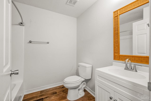 full bathroom with toilet, hardwood / wood-style floors, a textured ceiling, vanity, and tub / shower combination