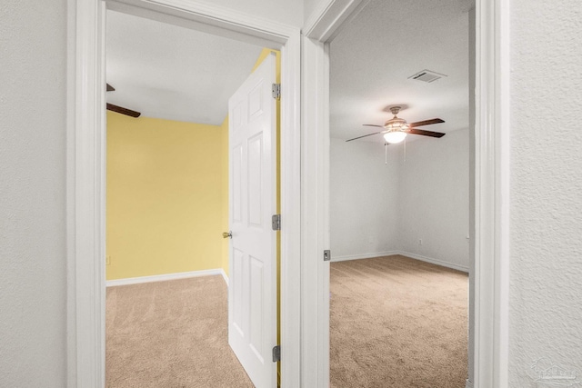 hallway featuring light colored carpet and a textured ceiling