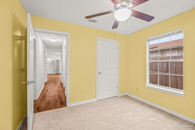 unfurnished bedroom featuring light carpet, ceiling fan, and stainless steel fridge