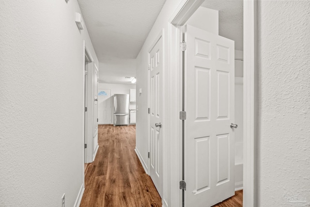 hallway with dark wood-type flooring and a textured ceiling