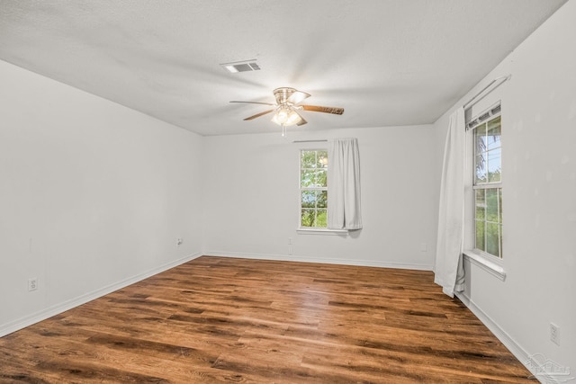 spare room featuring a textured ceiling, plenty of natural light, ceiling fan, and dark hardwood / wood-style flooring