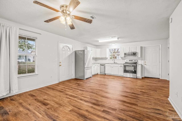 kitchen with white cabinets, appliances with stainless steel finishes, hardwood / wood-style flooring, and plenty of natural light