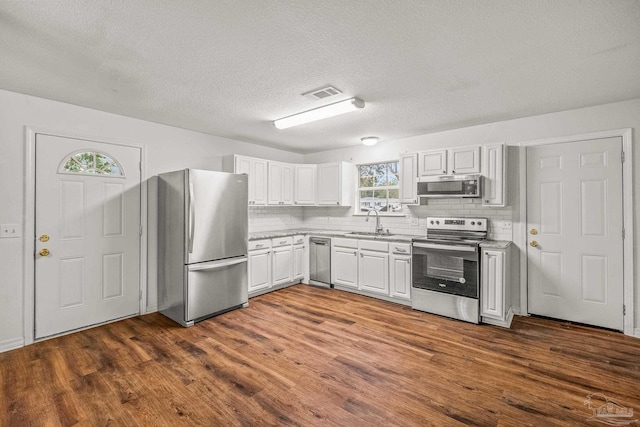 kitchen with stainless steel appliances, white cabinetry, sink, tasteful backsplash, and dark hardwood / wood-style flooring