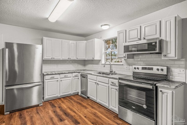 kitchen with stainless steel appliances, dark hardwood / wood-style flooring, sink, tasteful backsplash, and white cabinetry