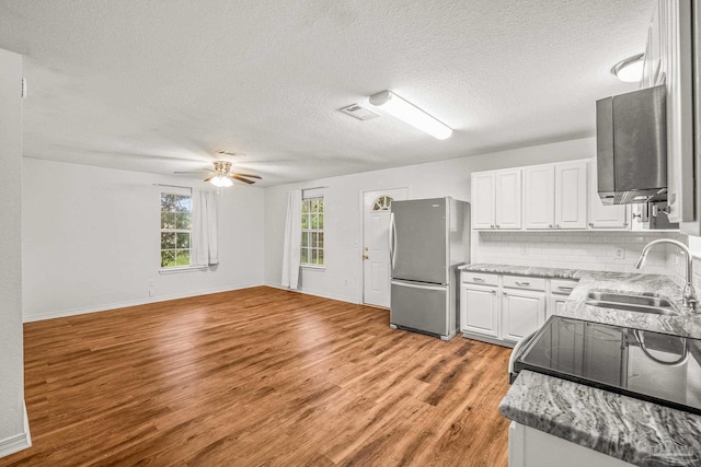 kitchen featuring stainless steel refrigerator, sink, a textured ceiling, white cabinets, and light wood-type flooring