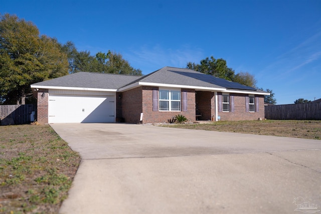 single story home with a garage, a front lawn, and solar panels