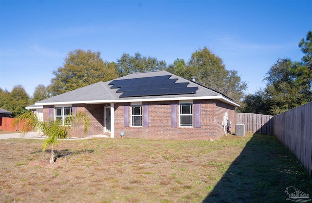 view of front of house with a front lawn, cooling unit, and solar panels