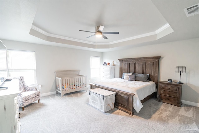 bedroom featuring a raised ceiling, ceiling fan, ornamental molding, and light carpet