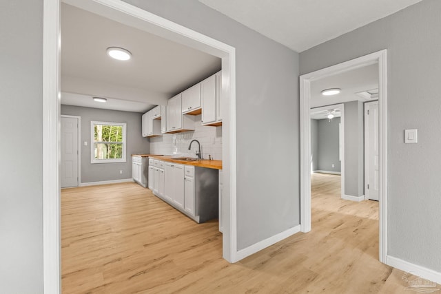 kitchen featuring sink, white cabinetry, wooden counters, light hardwood / wood-style flooring, and backsplash