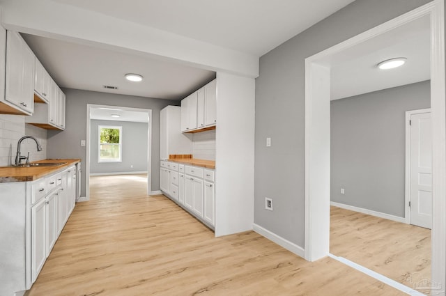 kitchen featuring white cabinets, sink, wooden counters, and backsplash