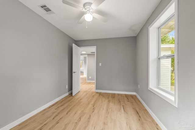 unfurnished bedroom featuring ceiling fan, multiple windows, and light wood-type flooring