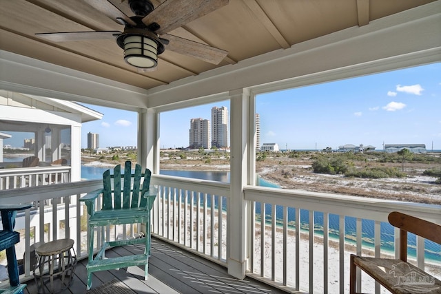 wooden terrace featuring a city view, a ceiling fan, and a water view